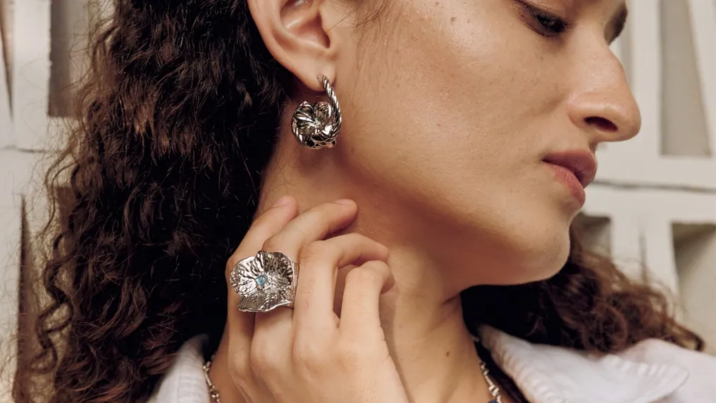A woman wearing a flower earring and matching ring from MONSECRET's Endless Summer collection
