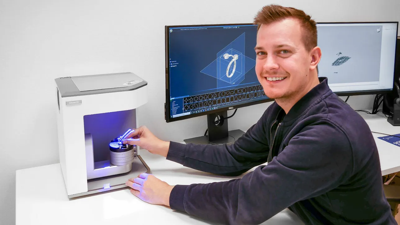 A jeweler scanning a ring on a desktop Artec Micro, the 3D model open on the monitors beside him